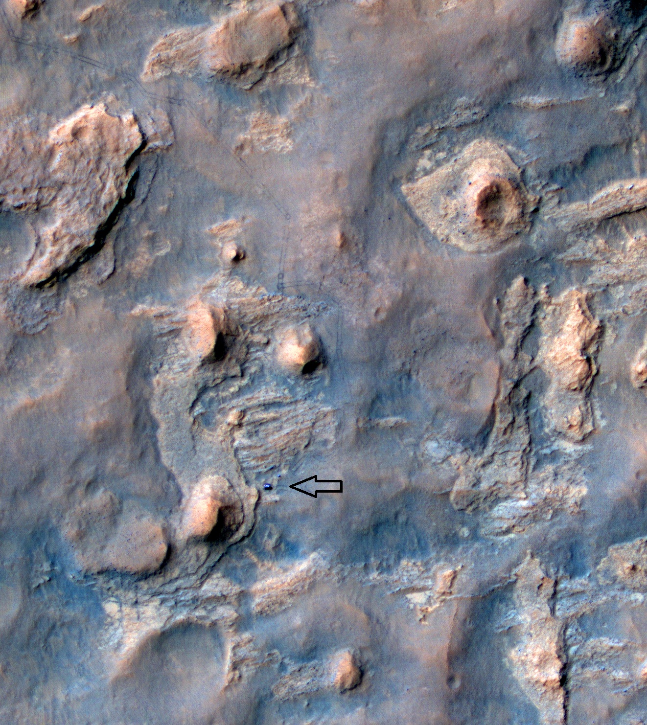 Curiosity est visible [flèche] sur cette photo, en couleur améliorée, prise par la caméra HiRise de Mars Reconnaissance Observer en orbite autour de Mars (source NASA/JPL)