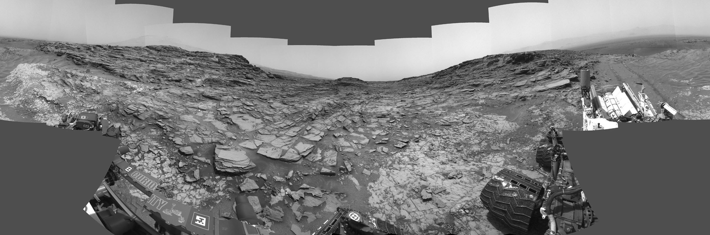Ce panorama à 360 ​° a été réalisé à partir d'images prises par la caméra de navigation (Navcam) du rover Curiosity de la NASA. Il montre les environs d'un site en bas du Mont Sharp, où le rover a passé son 1000e jour martien (ou Sol). Le Sol 1000 de la mission Curiosity correspondait au 30 mai 2015. Les images composant cette scène ont été prises au Sol 997 ( le 27 mai 2015). Le site est une vallée juste en dessous du "Marias Pass" (sorte de petit col) en bas du mont Sharp.