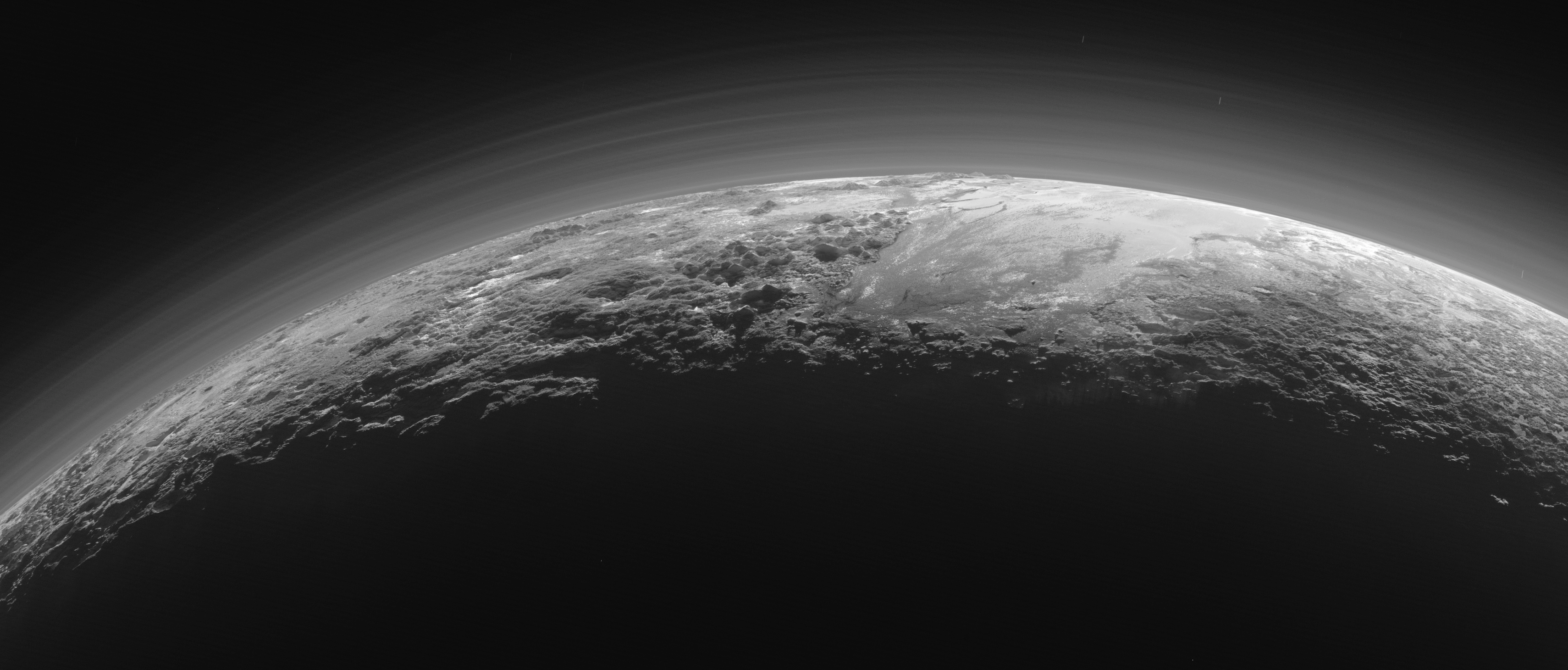 Image de Pluton prise par la sonde New Horizons le 14 juillet 2015 à une distance de 18 000 kilomètres. L'étendue lisse du Spoutnik Planum (à droite) est flanquée à l'ouest (à gauche) par des montagnes escarpées allant jusqu'à 3 500 mètres d'altitude. L'image couvre 1250 kilomètres de large. (Crédits: NASA / JHUAPL / SwRI)