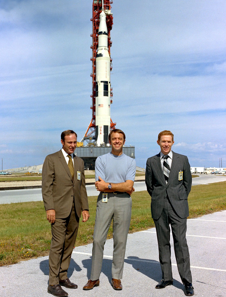 Ed Mitchell (gauche), Al Shepard, et Stu Roosa posant devant leur Saturn V durant le roulage au pas de tir le 9 Novembre 1970 (credit NASA)